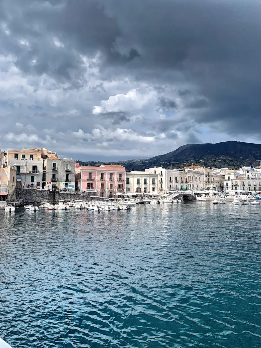 white and brown concrete building near body of water under cloudy sky during daytime