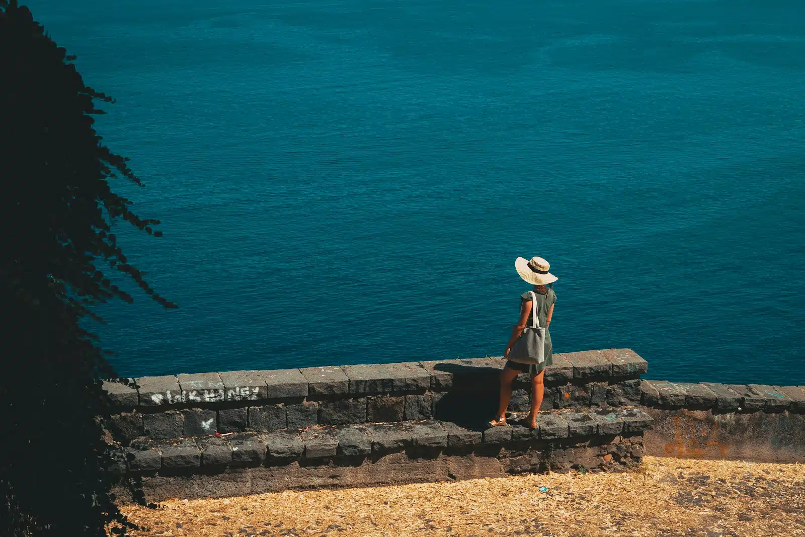 a person wearing a hat standing on a stone wall